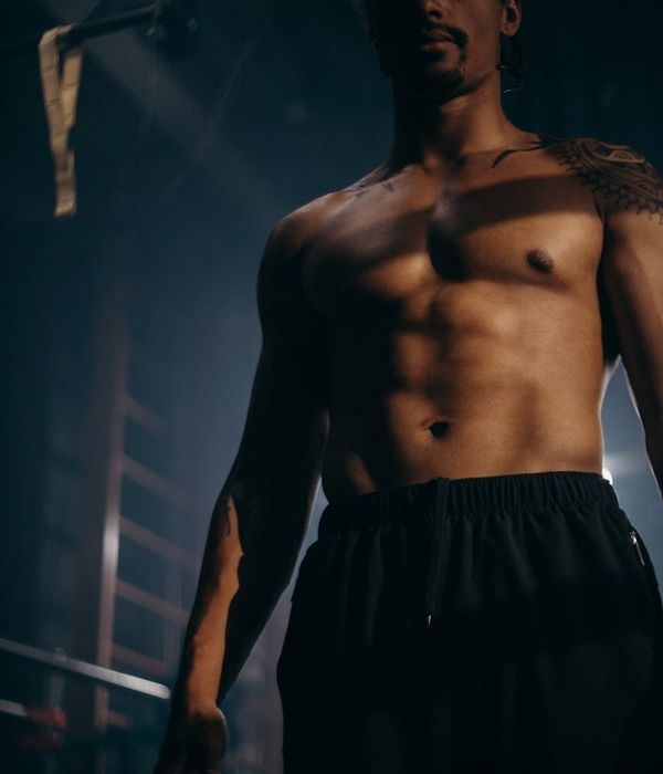 Athletic man performing strength movements in a dark gym